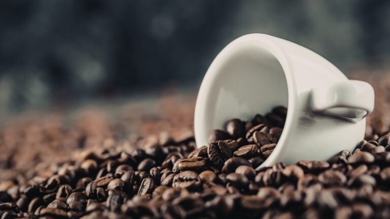 Coffee beans for energy with a blurred coffee cup in the background
