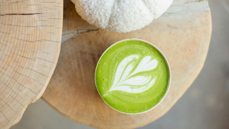 Hot matcha latte recipe with latte art on bamboo mat, overhead view